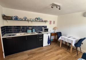 a kitchen with black cabinets and a table with a tablecloth at Mudeford Breeze in Mudeford +4 photos