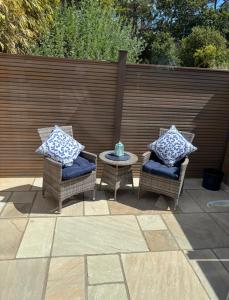two wicker chairs and a table on a patio at Mudeford Breeze in Mudeford