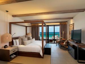 a hotel room with a bed and a television at Unico Hotel Riviera Maya Adults Only in Akumal