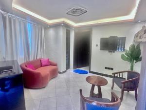 a living room with a pink chair and a tv at El Gado Casas in Kampala