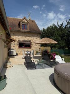 a patio with chairs and a table and a building at Le Refuge du Saule in Saint-Aubin-de-Locquenay