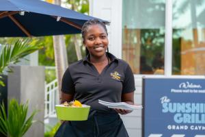 a woman holding a green bowl of food at The Sunshine Hotel and Suites in George Town