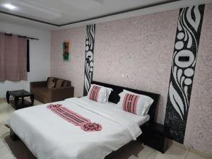 a bedroom with a large white bed and a chair at Nima Resort et Suites in Mandanou