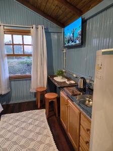 a kitchen with a sink and a tv on the wall at Vila dos Tropeiros in Lauro Müller