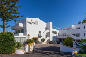 a large white building with a car parked in front of it at Lagoa Hotel in Lagoa