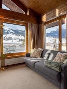 a living room with a couch and a large window at Wohnung Steinbock Savognin in Savognin