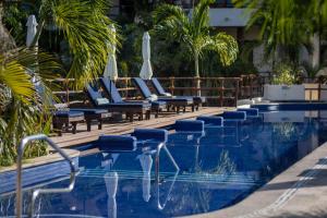 a swimming pool with lounge chairs and umbrellas at Porto Playa Condo Hotel and Beach Club in Playa del Carmen