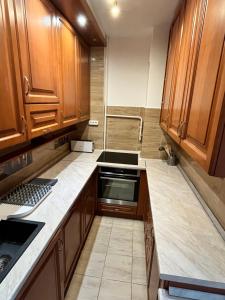a kitchen with wooden cabinets and a stove top oven at Battaville Apartment in Százhalombatta +2 photos
