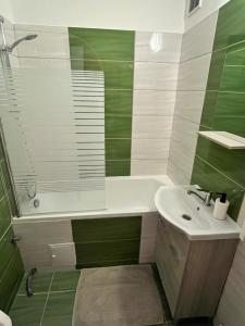 a green and white bathroom with a sink and a tub at Battaville Apartment in Százhalombatta