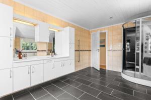 a large kitchen with white cabinets and black appliances at Spectacular nature experience at Norway's southern point! in Svenevik +72 photos