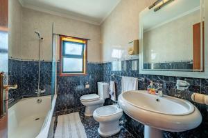 a bathroom with two toilets and a sink and a tub at Casa do Alto in Recarei +27 photos