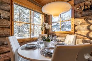 a dining room with a table and chairs and windows at HilleVilla by Holiday in Lapland in Ylläsjärvi