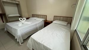 a room with two beds with white sheets at Hotel Gold Fish in Corumbá +19 photos