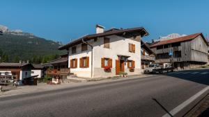 a building on the side of a road next to a mountain at Casa Amabile in Cortina dʼAmpezzo