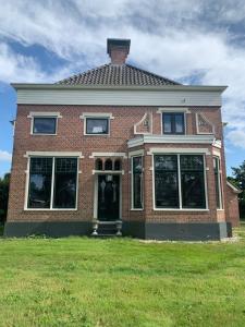 a red brick house with a grassy yard at Feel-Fine Guesthouse in Nieuw-Buinen +7 photos