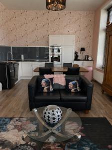 a living room with a black couch and a table at Feel-Fine Guesthouse in Nieuw-Buinen