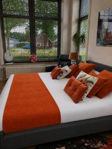 a bed with an orange blanket and pillows on it at Feel-Fine Guesthouse in Nieuw-Buinen