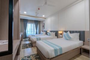 a hotel room with two beds and a television at Hotel TGR in Ankleshwar +42 photos