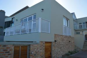 a white house with a balcony on top at 2 Bedroom sea view studio in Onrus in Hermanus