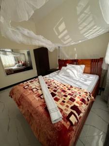 a bedroom with a bed with a comforter on it at Seneu Executive Residence in Mwanza