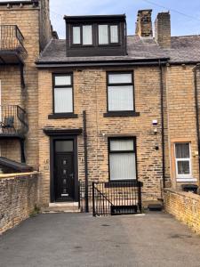 a brick house with a bench in front of it at Entire 3-Bed House-Jaquzzi Bath-Private Parking- suitable for contractors in Elland