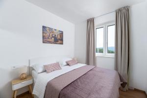 a white bedroom with a bed and a window at Apartman Tena in Barban
