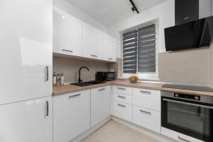 a white kitchen with white cabinets and a microwave at Apartman Tena in Barban