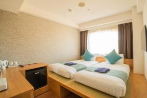 a hotel room with two beds and a desk at Osaka Kansai Airport Hotel Kansai Airport 2 station in Izumi-Sano