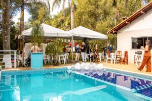 a group of people standing around a swimming pool at Chácara Eldorado in Amparo