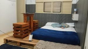 a bedroom with a bed with a blue blanket at Fenergia Hospedagem Flexível in Pouso Alegre +6 photos