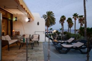a balcony with chairs and a table and palm trees at Casa Sherazad in Tías
