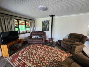 a living room with two chairs and a flat screen tv at Hogsback Misty Oaks Cottage in Hogsback