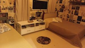 a small room with two beds and a tv at Fenergia Hospedagem Flexível in Pouso Alegre
