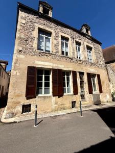 an old stone building with windows on a street at Gîte L'Atelier in Avallon