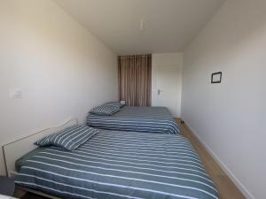 two beds in a small room with striped sheets at La Maison Menhiria in Dol-de-Bretagne