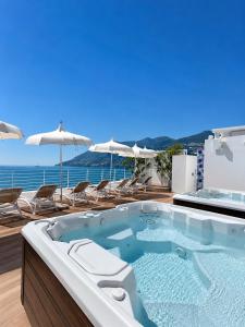 a hot tub on a deck with chairs and umbrellas at Hotel Club Due Torri in Maiori