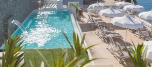 a swimming pool with chairs and umbrellas next to the ocean at Hotel Club Due Torri in Maiori