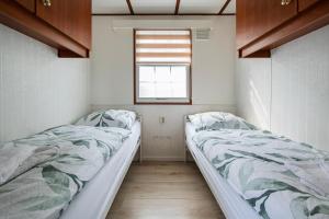 two beds in a small room with a window at 80, Midden in de natuur - Airco! in Oisterwijk