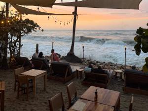 a group of people sitting at tables on the beach at Makao Beach Hotel in Palomino