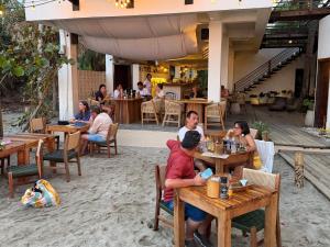 a group of people sitting at tables in a restaurant at Makao Beach Hotel in Palomino