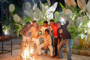 a group of people posing for a picture in front of a fire at Swastha Royals Wayanad in Kaniyāmbetta +103 photos