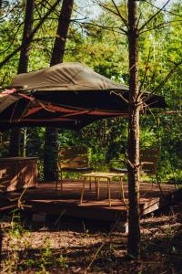 a table and chairs on a wooden deck with an umbrella at Dacza Puchacza Hamaki in Stare Osieczno +91 photos