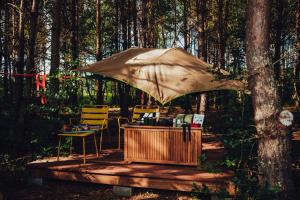 a table and chairs under an umbrella in the woods at Dacza Puchacza Hamaki in Stare Osieczno