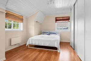 a bedroom with a bed and two windows at Cozy apartment in South of Norway! in Svenevik