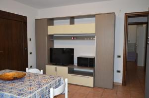 a room with a table with a television and a kitchen at il nido in Capoterra