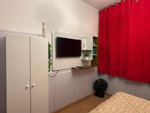 a room with a tv and a red curtain at Apartamento para duas pessoas com cama de casal in Teresópolis