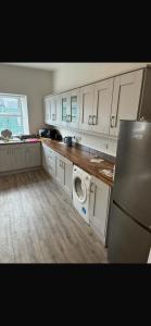 a kitchen with white cabinets and a washer and dryer at The Urban Haven in Limerick