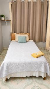 a bed with a white blanket and a yellow towel on it at Cómo en casa CDE in Ciudad del Este +1 photo