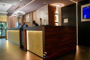 a lobby with a bar with three people sitting at it at Hotel La Falaise Bonapriso in Douala +188 photos
