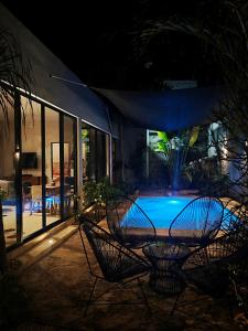 a patio with two chairs and a pool at night at Casa Ramon Merida 2 BR AC Private Pool Centro in Mérida